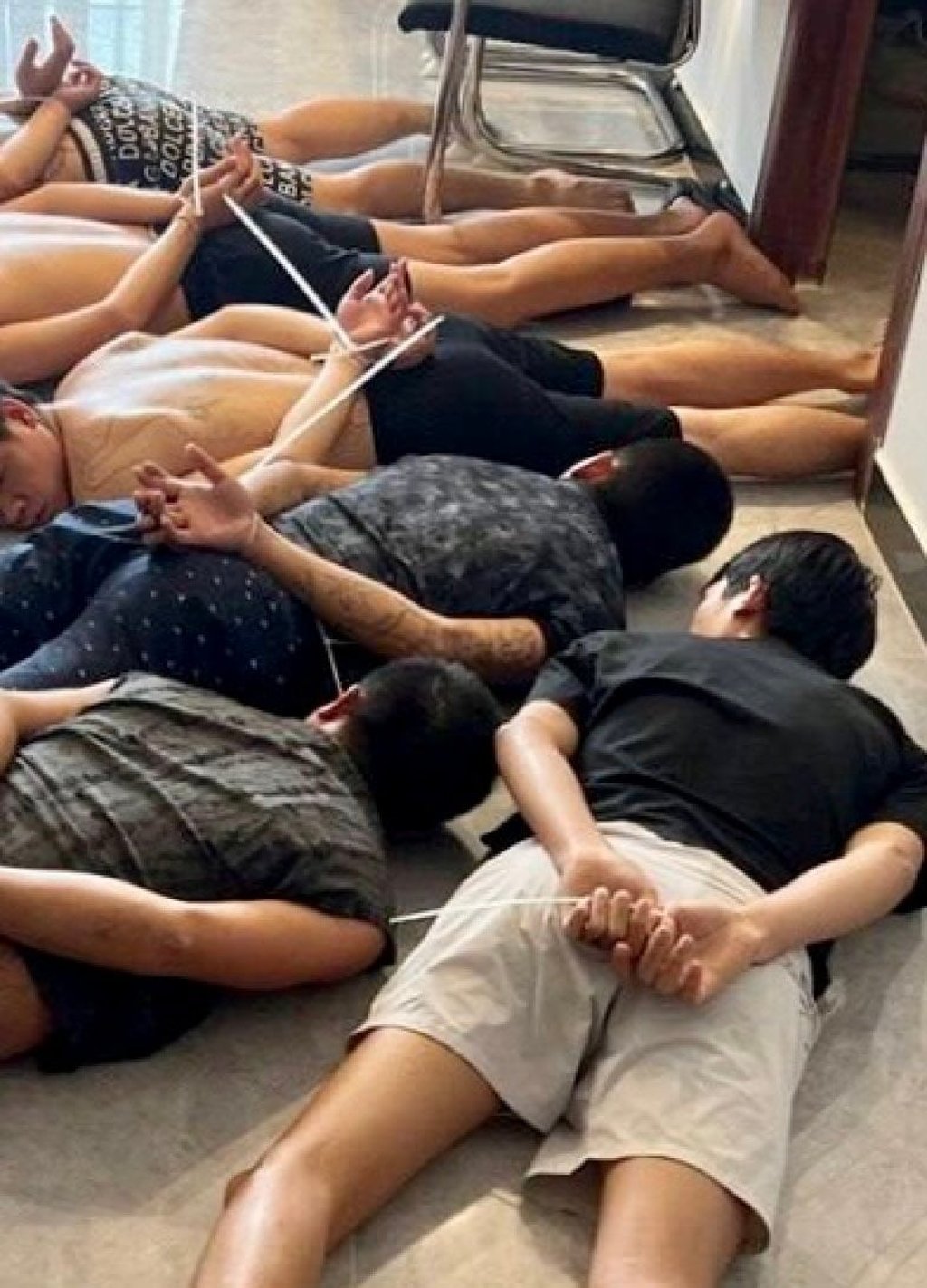 Suspects have their hands zip-tied after being detained during a police raid on a scam centre in Phnom Penh on July 16. Photo: EPA