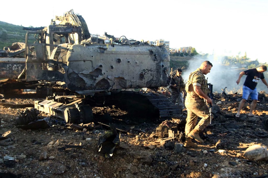 Lebanese soldiers walk next to a destroyed digger following an overnight Israeli strike in southern Lebanon earlier this month. Photo: AFP