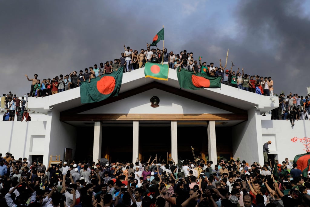 Anti-government protesters display Bangladesh’s national flag as they storm then prime minister Sheikh Hasina’s palace in Dhaka on August 5, 2024. Hasina later fled to India. Photo: AFP