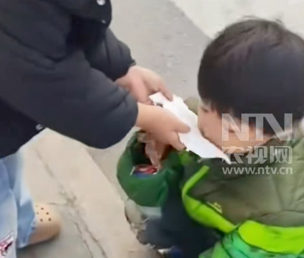 A passer-by helps little Yueyue blow her runny nose with a tissue as she sits on the street. Photo: Douyin
