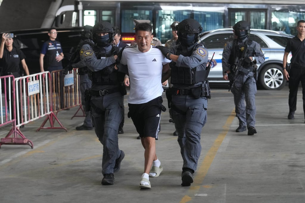 She Zhijiang, who is accused by Beijing of running illegal online gambling operations, is escorted by police at Suvarnabhumi International Airport in Thailand’s Samut Prakarn province ahead of being extradited to China on Wednesday. Photo: AP