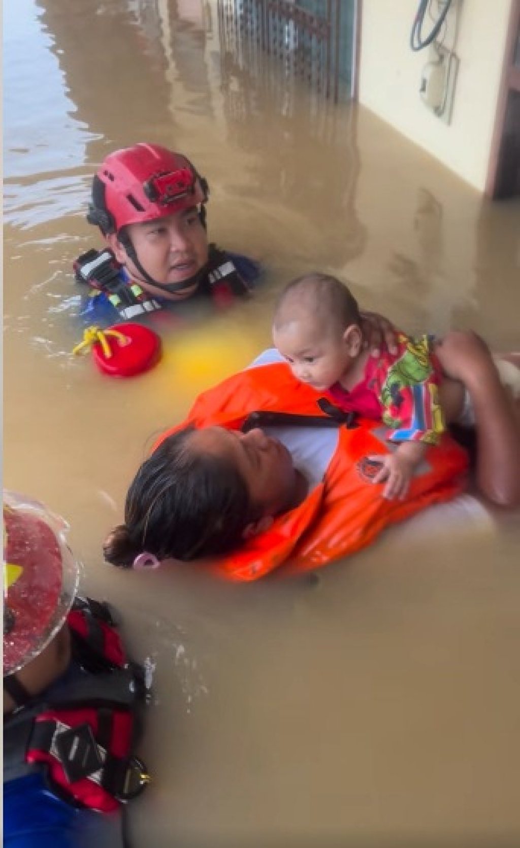 A baby rests on the chest of a woman in a life jacket as she is guided out from a flooded building in Hat Yai, Thailand. Photo: Facebook/เอกวัฒน์ ไชยจันลา เก่ง มหาศิลา