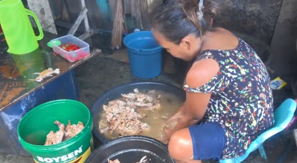 A Filipino woman washes the discarded meat in a basin before selling the leftovers to vendors. Photo: Douyin.