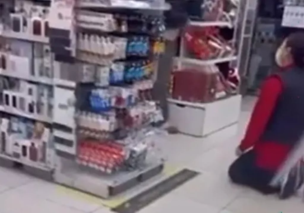 The humiliated member of staff is seen kneeling in front of shelves in the shop. Photo: X