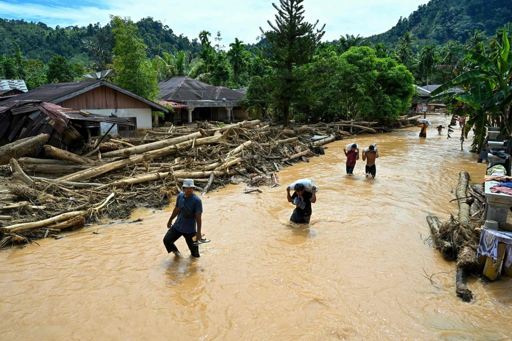 People wade through floodwaters in the aftermath of flash floods in Central Tapanuli, North Sumatra province, on Tuesday. North Sumatra suffered the heaviest toll with more than 300 people dead. Photo: AFP