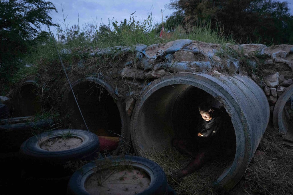 A Thai resident who fled clashes between Thai and Cambodian soldiers uses his mobile phone while taking shelter in Buriram province on Tuesday. Photo: AP
