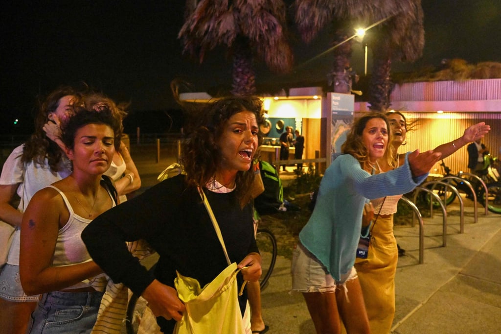 Youngsters react as they leave the site of an attack by gunmen at Bondi Beach on Sunday evening. Photo: AFP