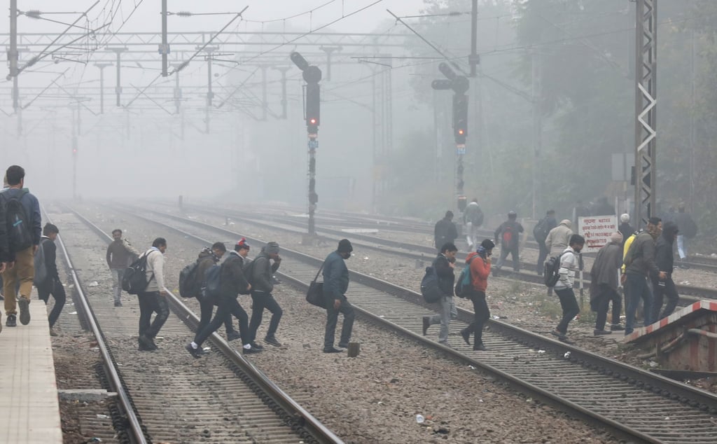 People walk on a railway track amid heavy smog on a winter morning in New Delhi on December 18. The winter smog is driving more patients with respiratory complaints to hospitals. Photo: EPA