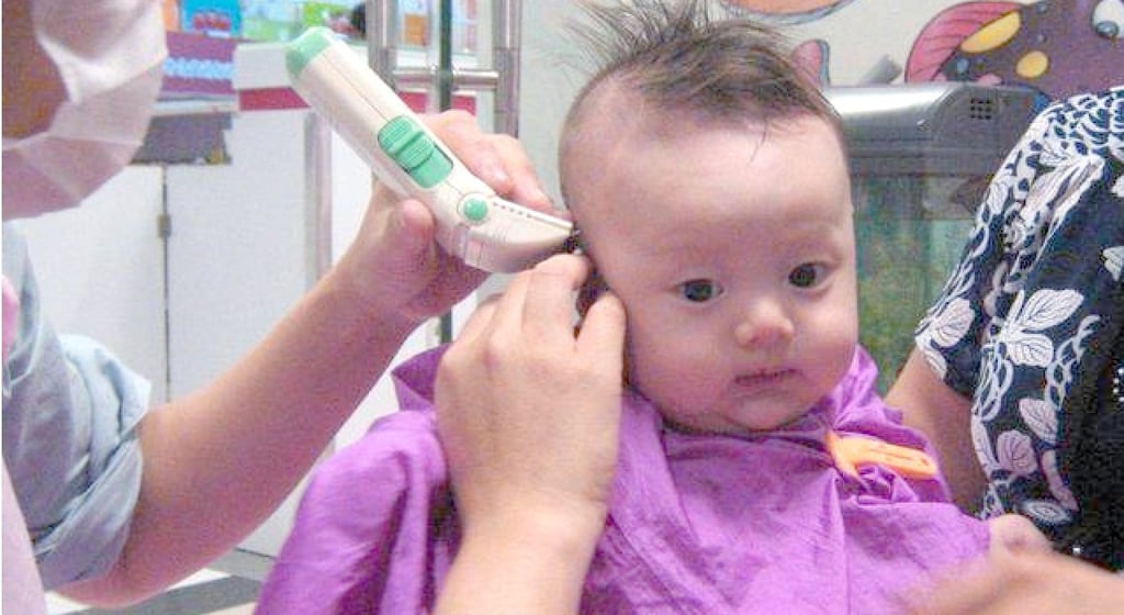 A somewhat apprehensive infant having its hair shaved by a barber. Photo: Baidu