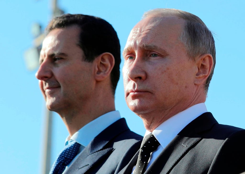 Putin and former Syrian president Bashar al-Assad watch troops at an airbase in Syria in December 2017. Photo: AP