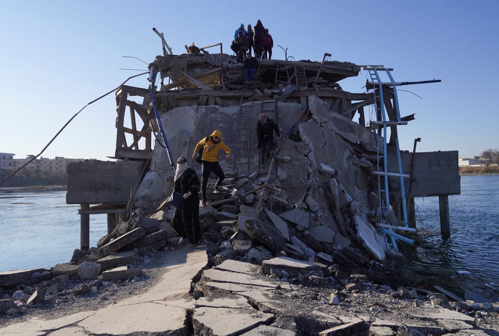 People cross a bridge that the Syrian army says was destroyed by the Kurdish-led Syrian Democratic Forces in Raqqa, Syria, on Tuesday. Photo: Reuters