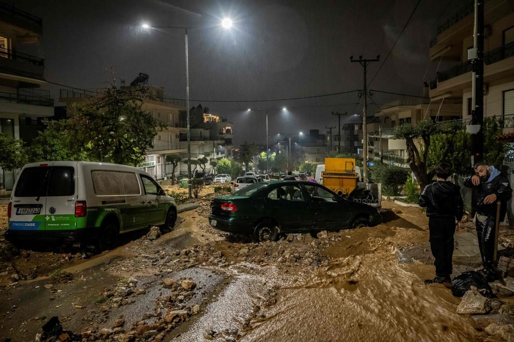 People try to clean a flooded street covered with rubble after heavy rainfall in Athens on Wednesday. Photo: AFP