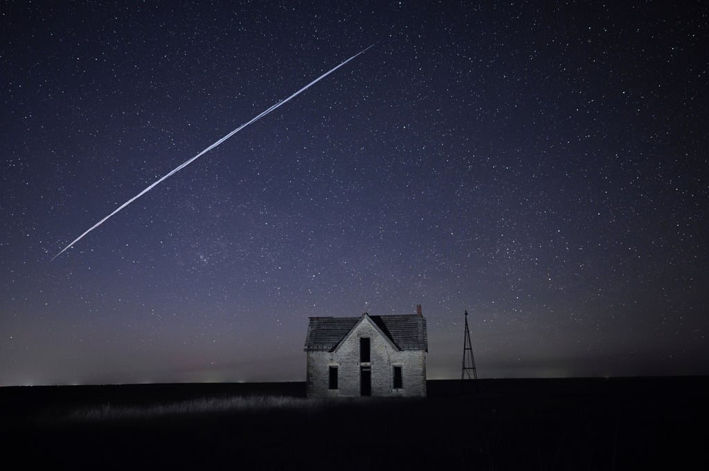 In this long exposure image, a string of SpaceX Starlink satellites passes over an old stone house near Florence, Kansas, in May 2021. Photo: AP