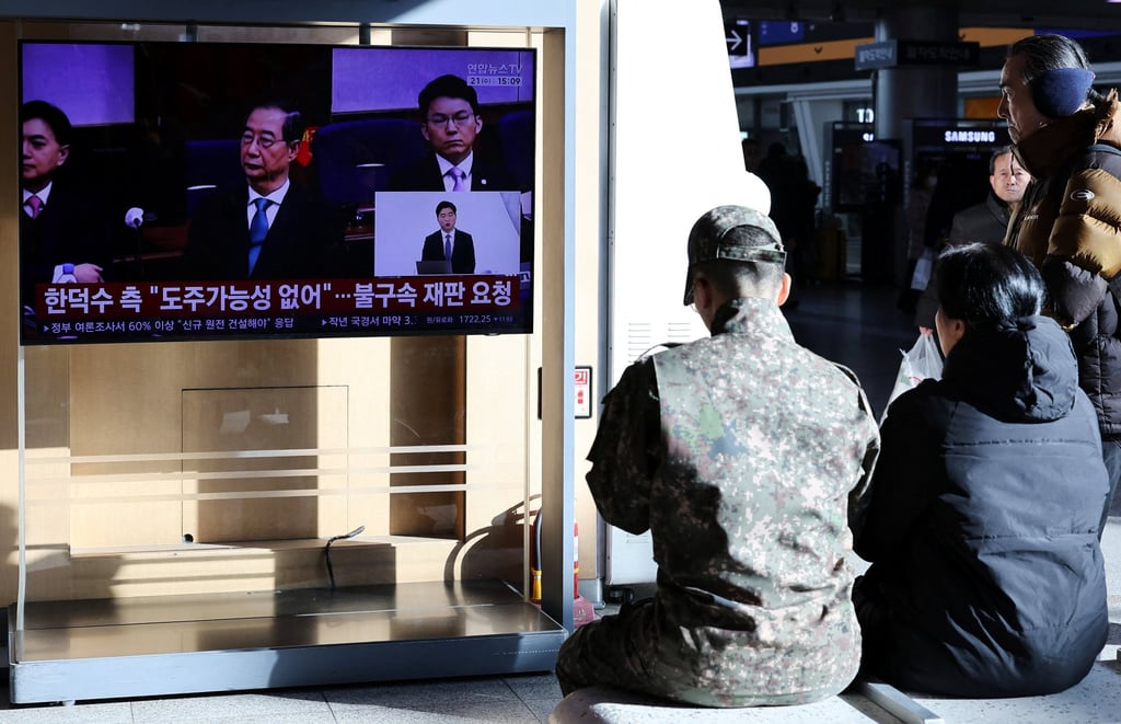 People watch a news report on Han Duck-soo’s court ruling on Wednesday. Photo: Reuters