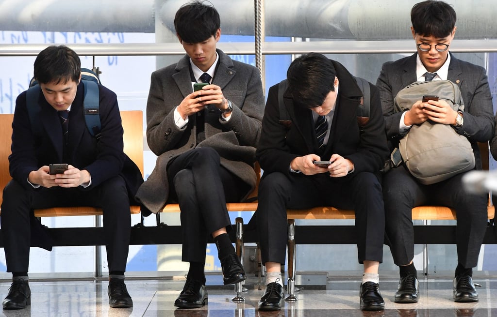 Job seekers look at their smartphones while during an employment fair in Seoul. Photo: AFP