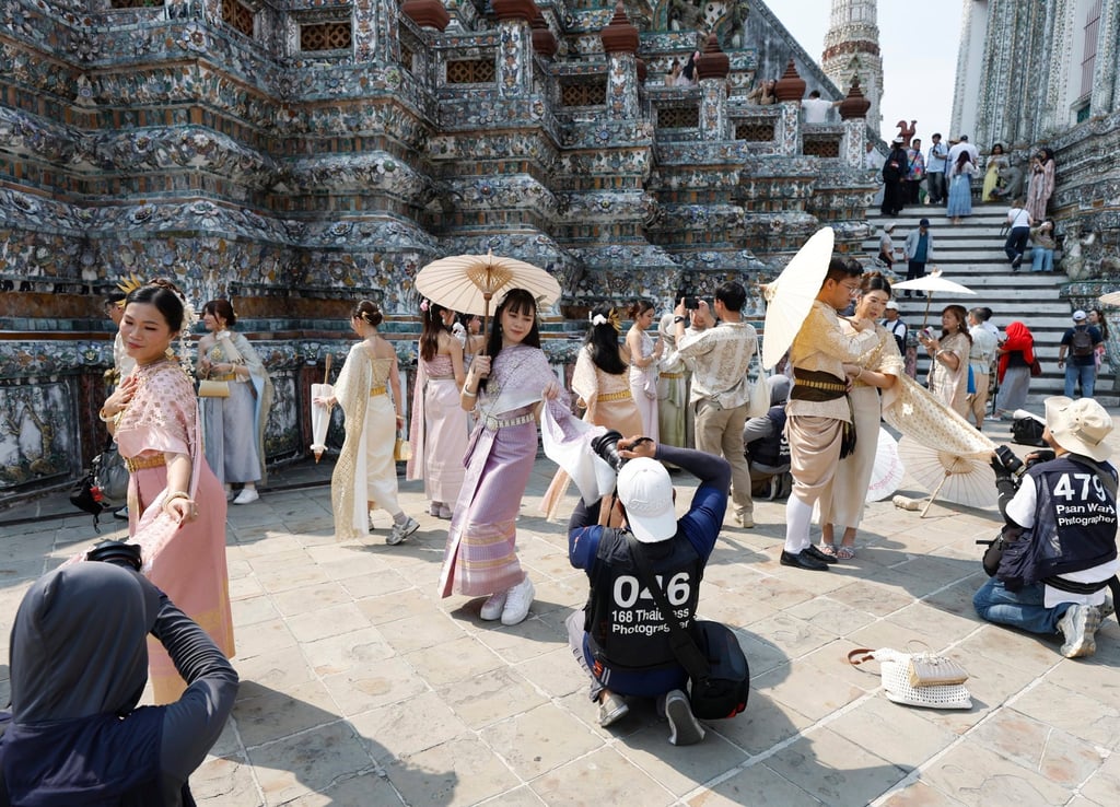 Tourists dressed in traditional Thai attire pose for souvenir photos at the Temple of Dawn in Bangkok on January 19. Photo: EPA
