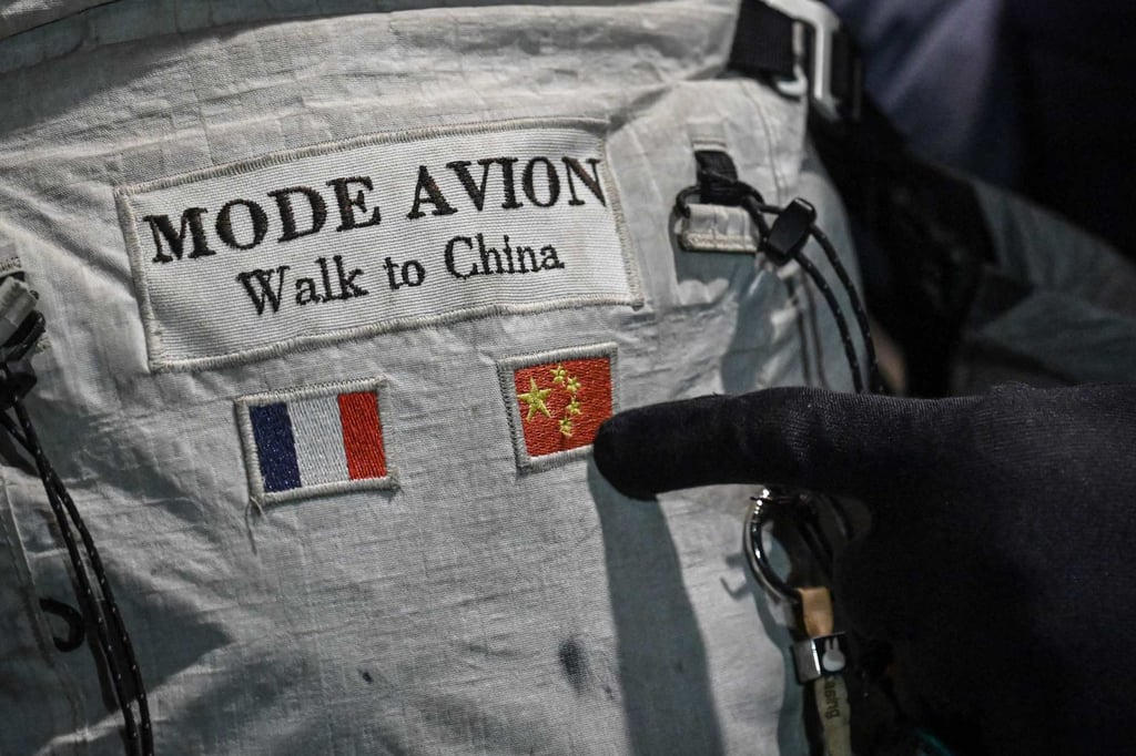 France’s Loic Voisot points at his backpack, which features both French and Chinese flags along with the words “Mode Avion, Walk to China” in Shanghai on Saturday. Photo: AFP