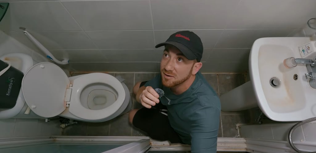 Drew Binsky crouches inside a gosiwon bathroom. Photo: YouTube/Drew Binsky