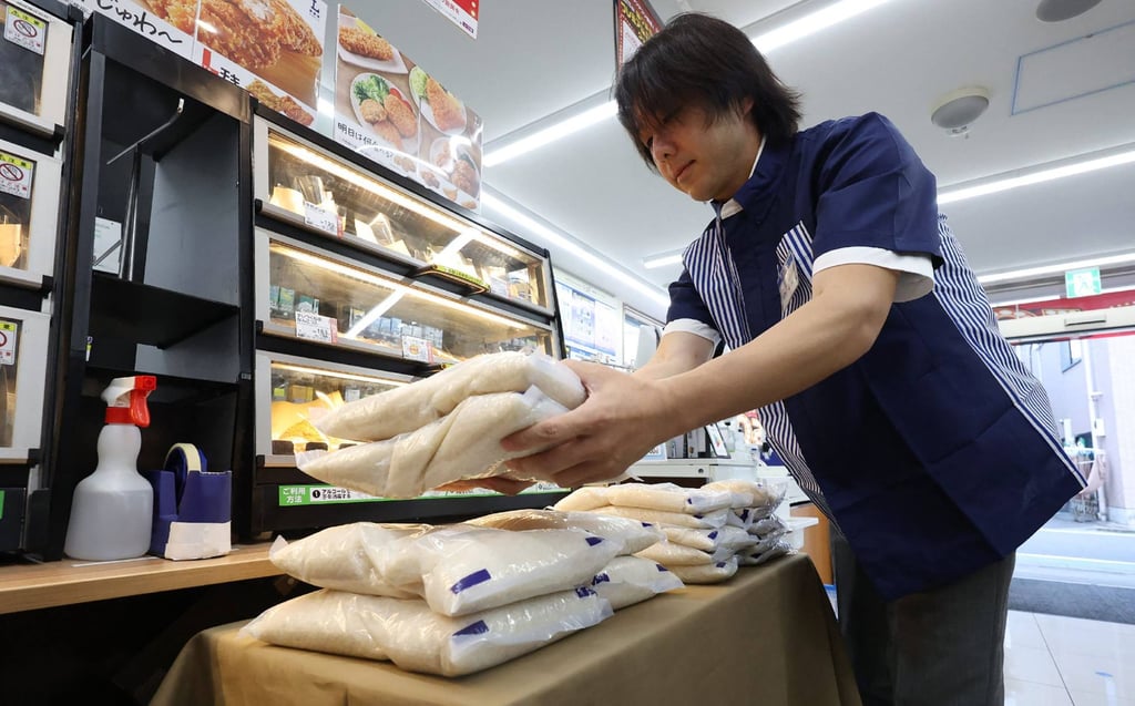 A member of staff displays bags of rice a Lawson convenience store in Tokyo last year. Rice prices in Japan have soared by around two-thirds. Photo: AFP