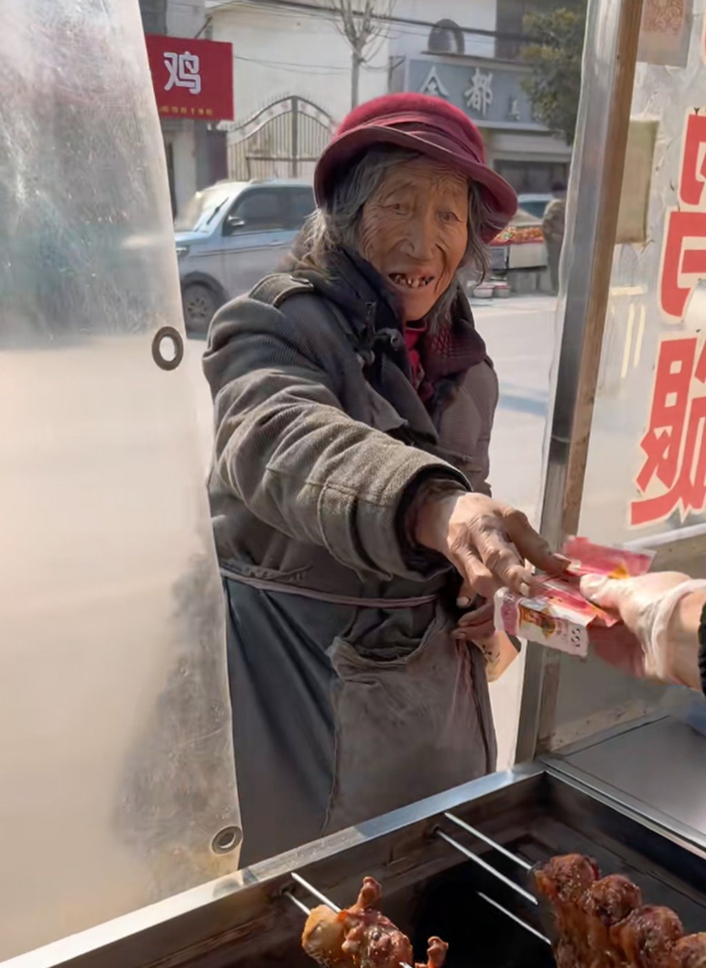 The elderly woman hands her “hell money” through the window of the food stall. Photo: Douyin