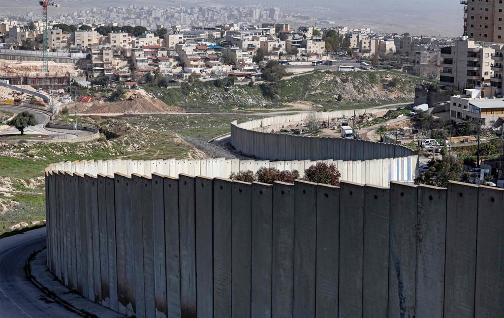 The Israeli settlement of Pisgat Zeev (left), built in a suburb of the mostly Arab East Jerusalem, is seen behind Israel’s separation barrier on Monday. Photo: AFP