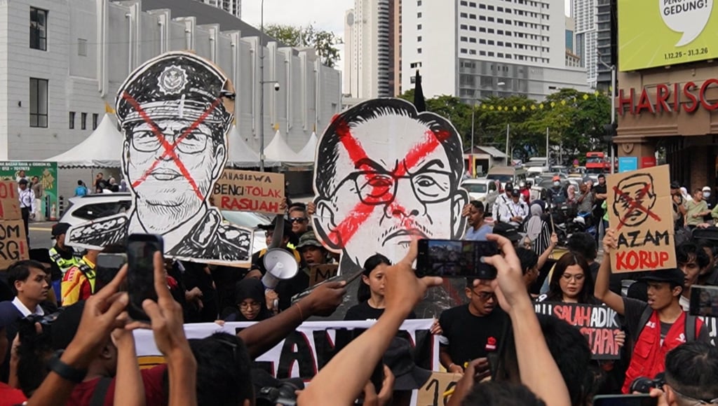 Black-clad protesters carry signs portraying Azam Baki (left) and Malaysian Prime Minister Anwar Ibrahim at the rally in the capital on Sunday. Photo: X/Rafizi Ramli