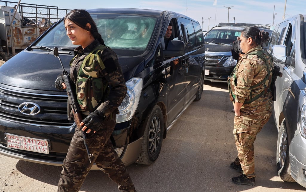 Syrian Democratic Forces members secure the area as vans carrying Australian family members of suspected Islamic State militants head to the airport on Monday. Photo: AP