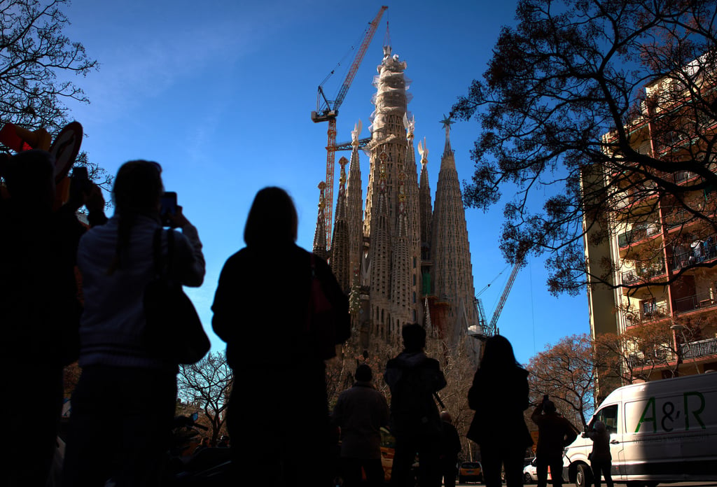 People watch as a crane lifts the upper arm of the cross onto the Tower of Jesus Christ on Friday. Photo: AP