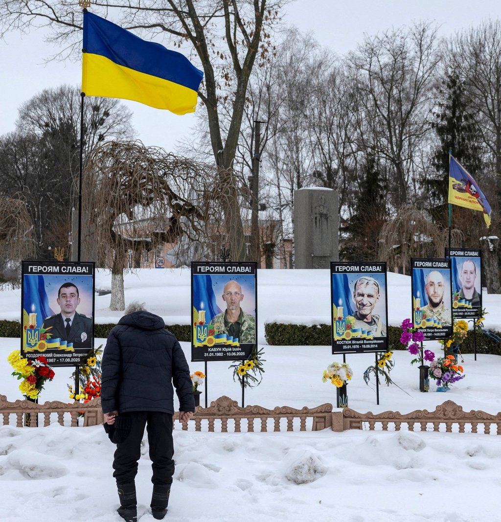 A man pays respects to his fallen relative at a memorial site for Ukrainian servicemen who died fighting the invading Russian army in Dzenzelivka on February 4. Photo: Reuters