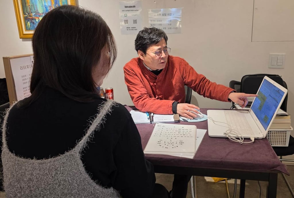 A Japanese tourist receives a “saju” reading from a fortune teller near Hongik University in Seoul on February 10. Photo: The Korea Times