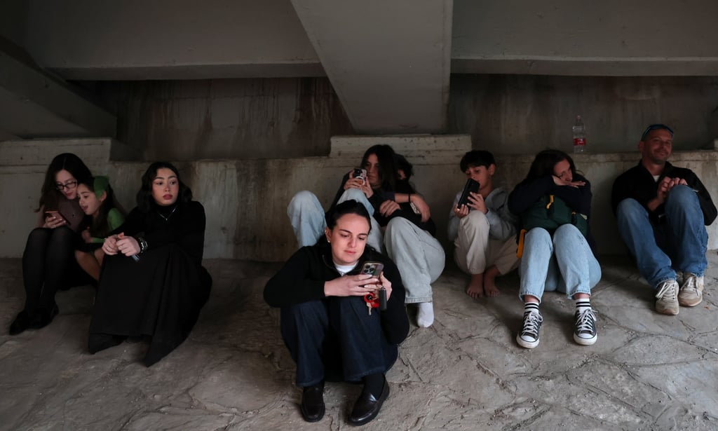 People take cover under a bridge as air-raid sirens sound near Israel’s Ben Gurion International Airport on Monday. Photo: EPA