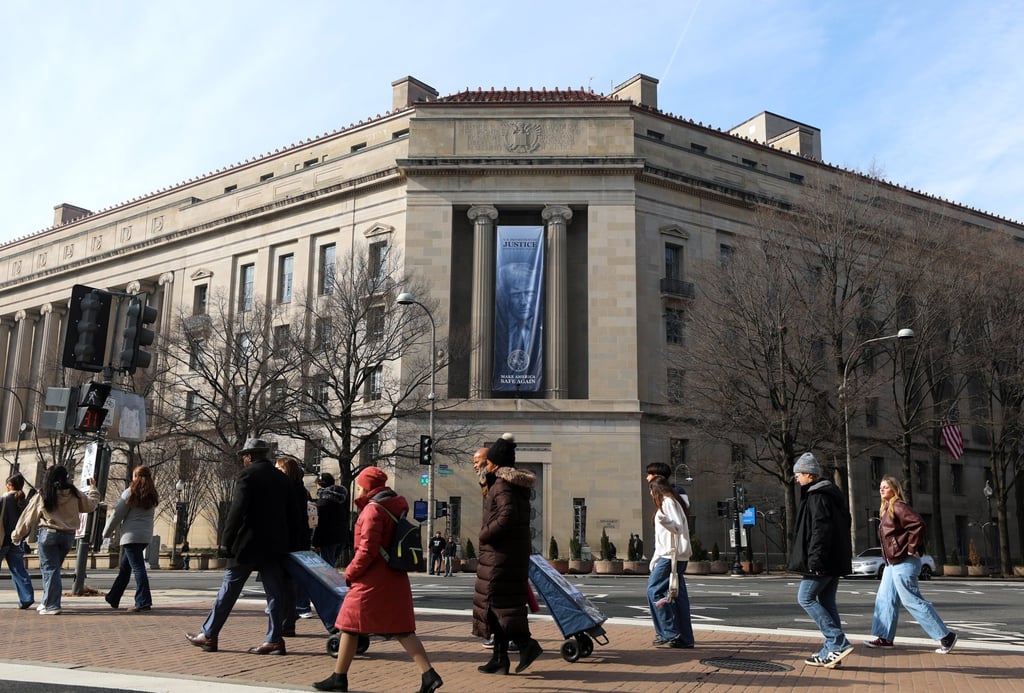 Tourists walk past a banner featuring US President Donald Trump hanging outside the Department of Justice in Washington on Friday. Photo: AP