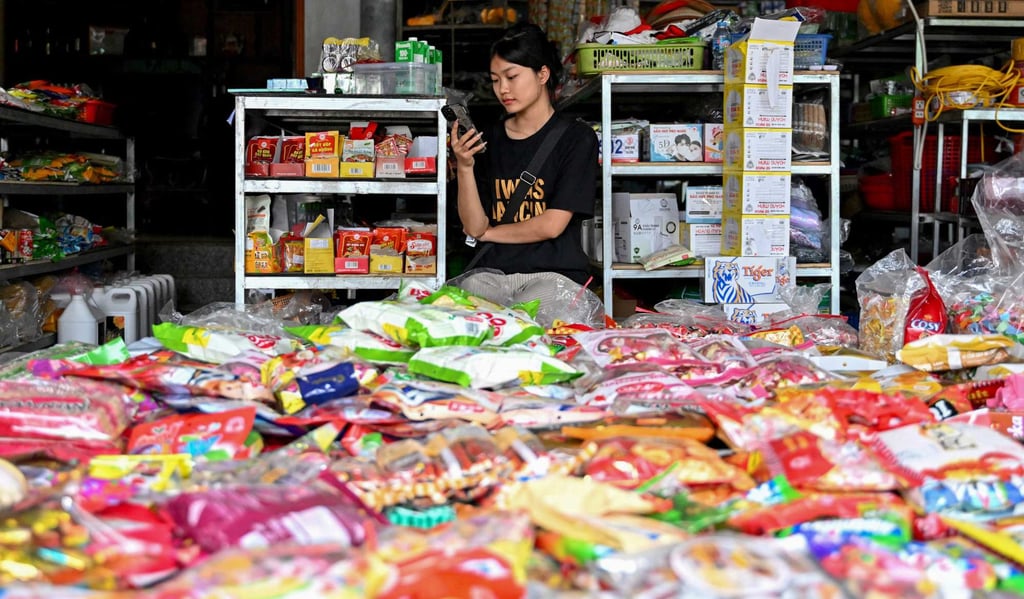 A Vietnamese shopkeeper uses her phone while waiting for customers at a grocery store in Hanoi on February 27. Photo: AFP