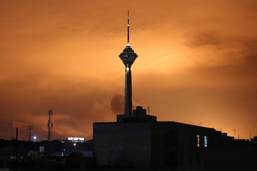 The sky behind Milad Tower, Iran’s tallest tower, is lit up following air strikes in Tehran on Saturday. Photo: AFP