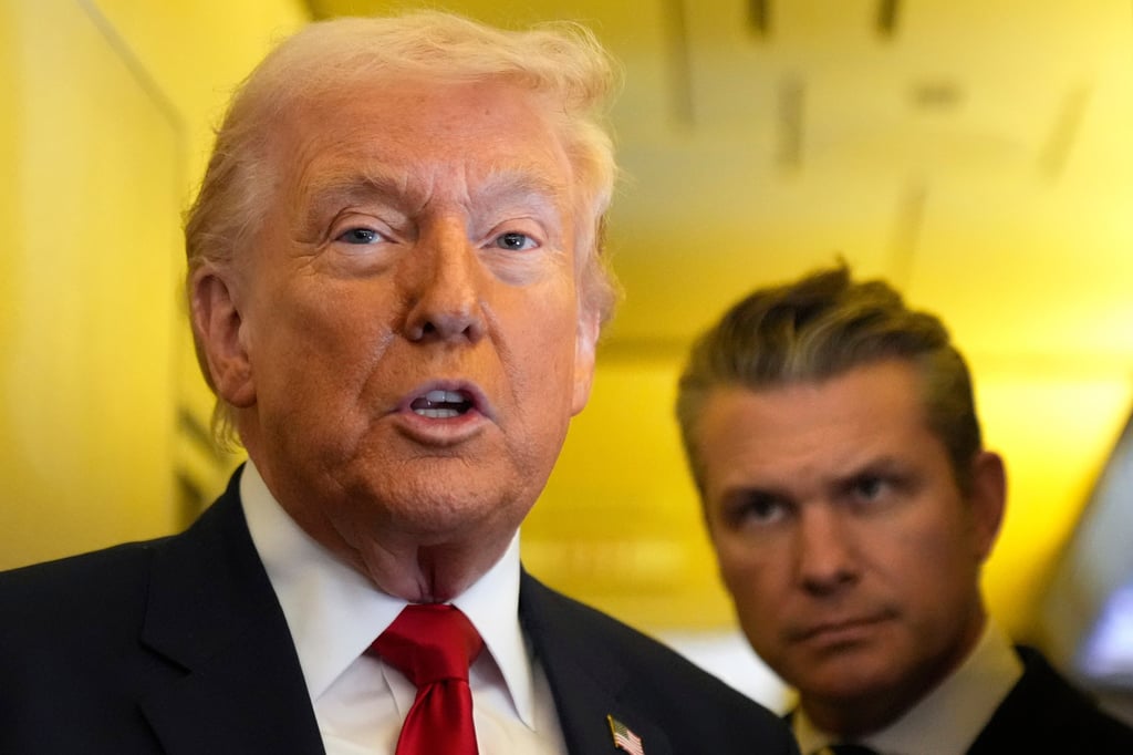 US President Donald Trump speaks to reporters as Defence Secretary Pete Hegseth listens while travelling on Air Force One on Saturday. Photo: AP