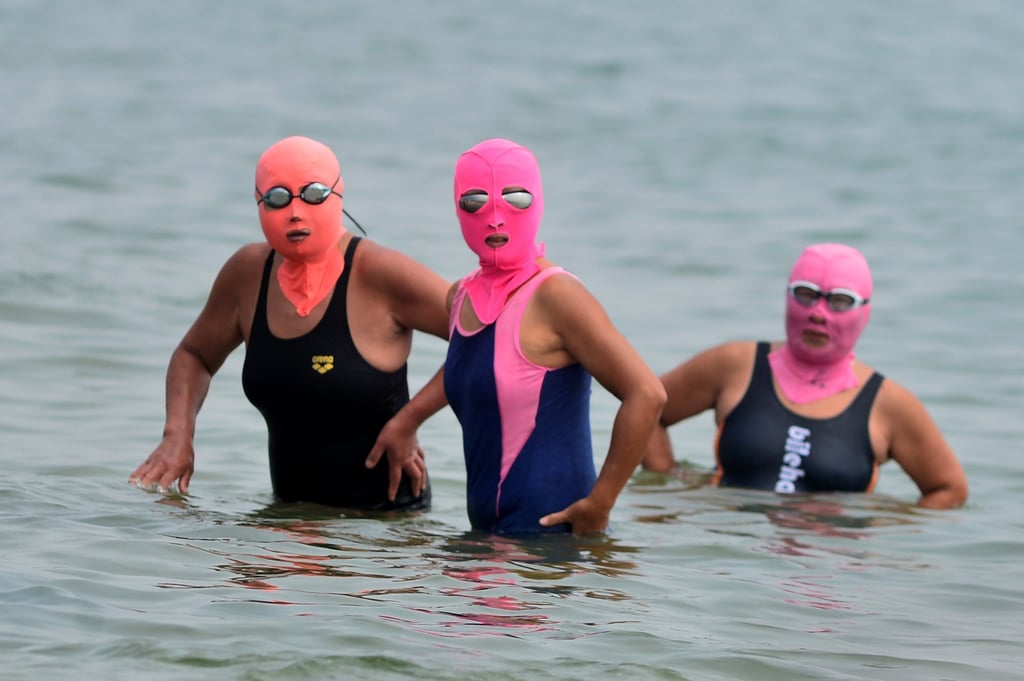 Three women wearing so-called facekinis to cool off while they bathe in the sea in China. Photo: Getty Images
