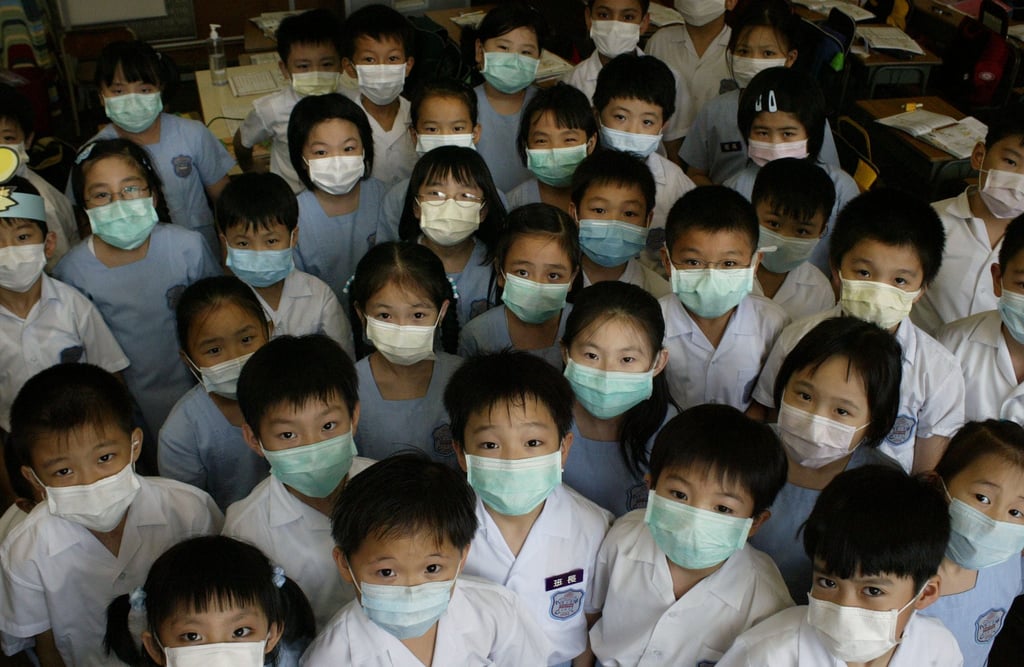 S.K.H. St. Peter’s Primary School students in Shek Tong Tsui prepare to take off their face masks after the World Health Organization announced the removal of Hong Kong from a list of Sars-affected areas. June 23, 2003. Photo: Oliver Tsang