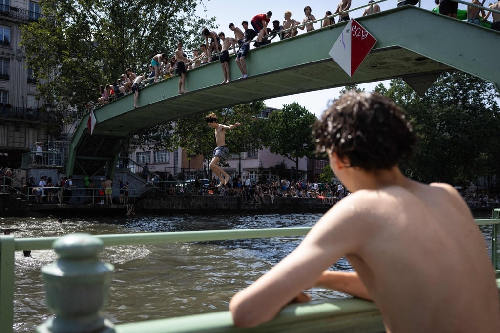 Youths jump into the Canal Saint-Martin during a heatwave in Paris on Wednesday. France experienced its hottest day ever recorded on Wednesday, surpassing the record set the previous day. Photo: AFP