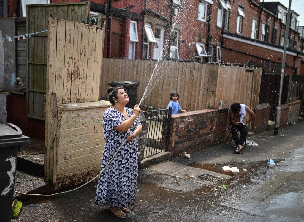 A woman sprays water to cool down the alley by her home in Leeds, northern England, on Thursday. Photo: AFP