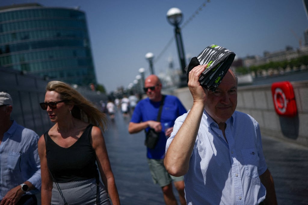 A man uses a shopping bag to try to shield his face from the sun while walking near Tower Bridge, London, on Thursday amid a heatwave, as Britain experiences record temperatures. Photo: Reuters