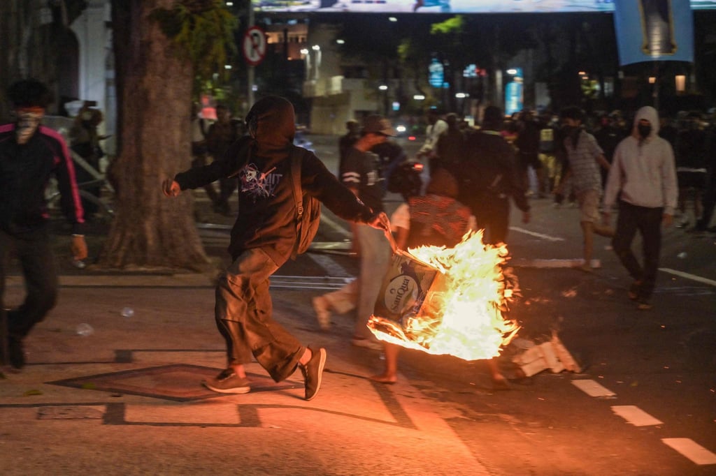 A student throws a box that has been set on fire at riot police during a protest in Surabaya on Friday. Photo: AFP
