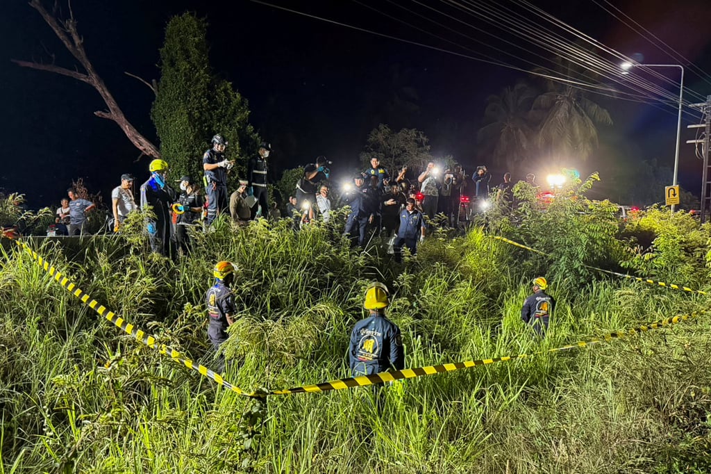Rescue workers, police officers and forensic technicians search a grassy area near a railway track before police found a suitcase containing the body of a 17-year-old Thai girl in Pattaya on Saturday. Photo: Reuters