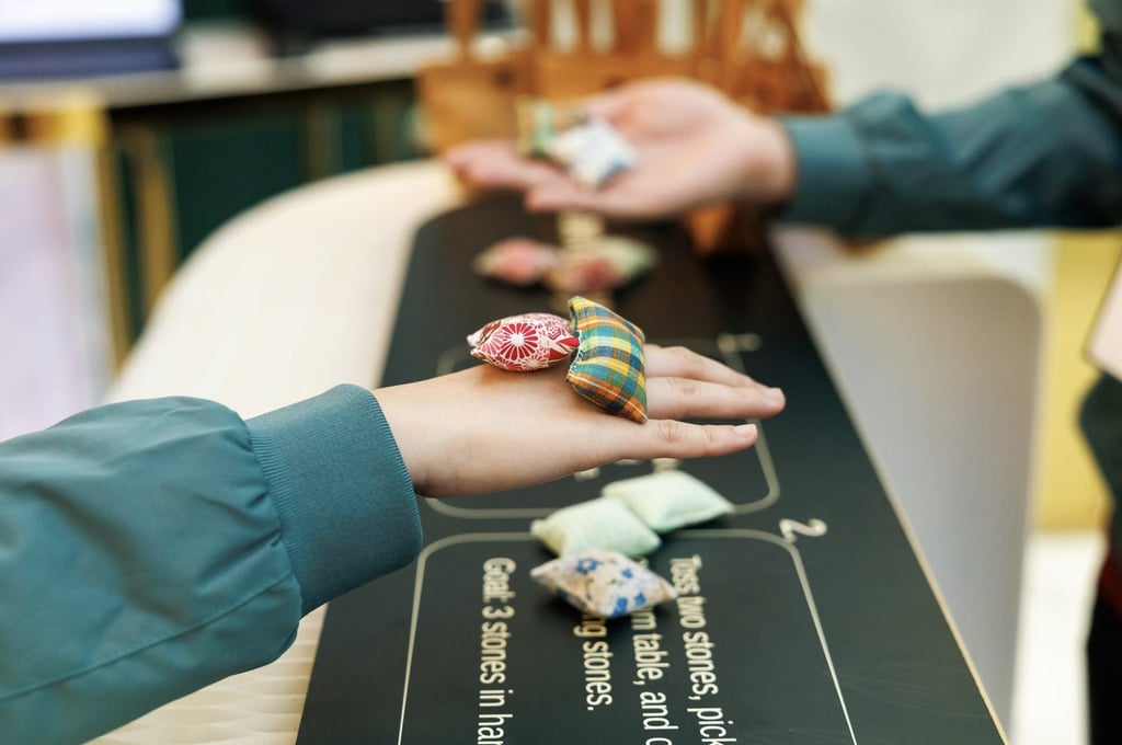 Players take part in a game of ‘five stones’ using pieces specially handcrafted for the summit by elderly artisans from Gingko House.