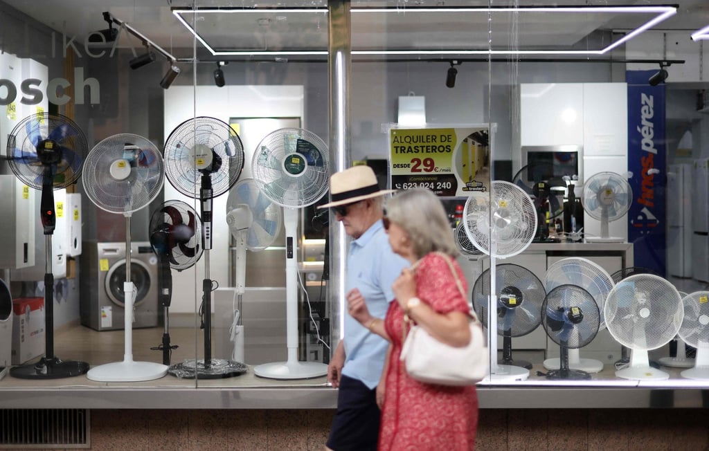 People in Madrid, Spain, walk past a shop selling fans during a heatwave on Thursday. Photo: AFP