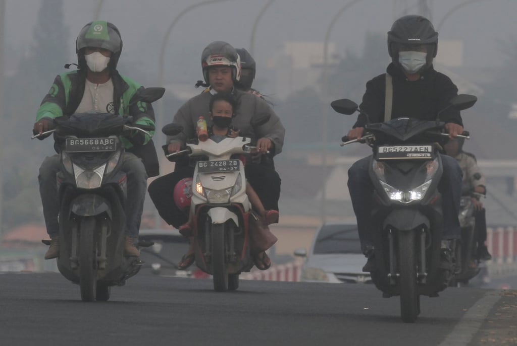 Riders wear masks as they pass through the haze from forest fires in Palembang, South Sumatra, in October 2023. Photo: AP