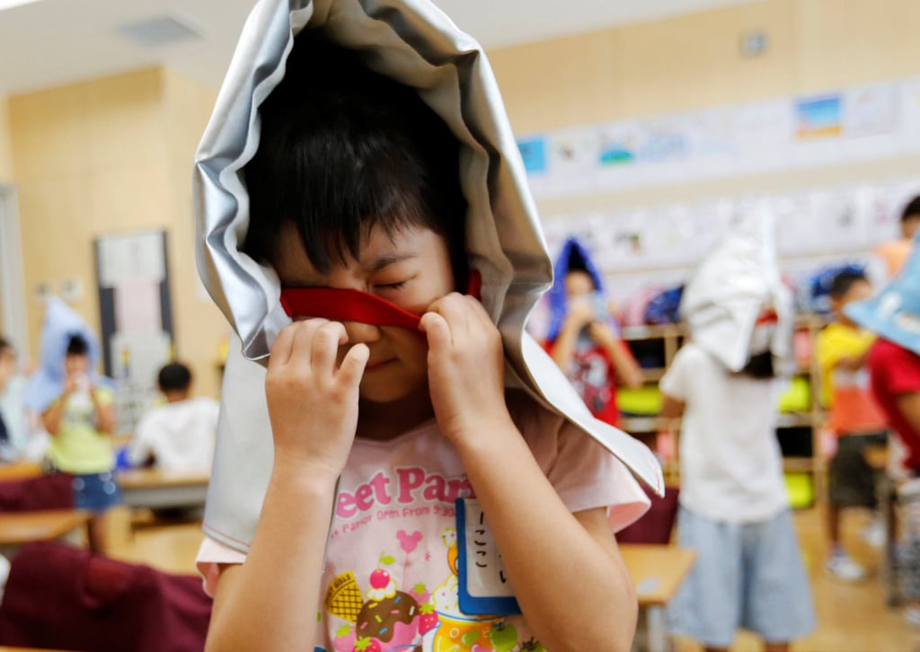 Schoolchildren wear padded hoods to protect them from falling debris during an earthquake simulation drill at a primary school in Tokyo in 2018. Photo: Reuters
