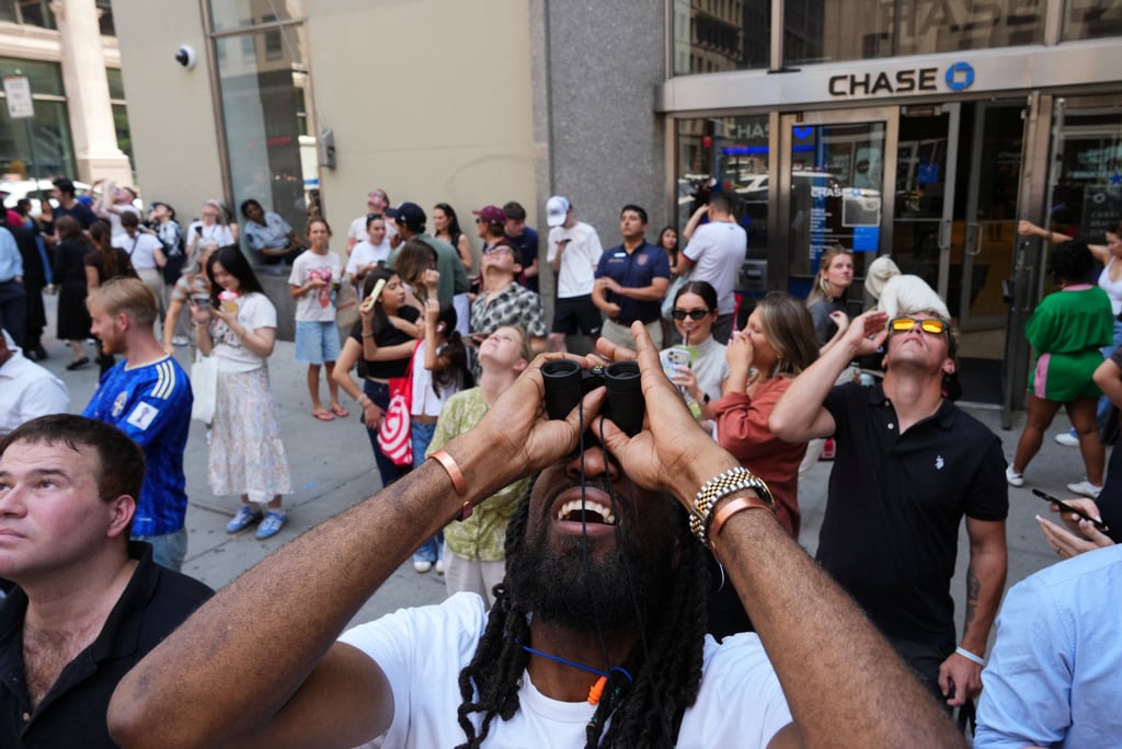 People look up at two people displaying a banner atop the Empire State Building in New York on Wednesday. Photo: Reuters
