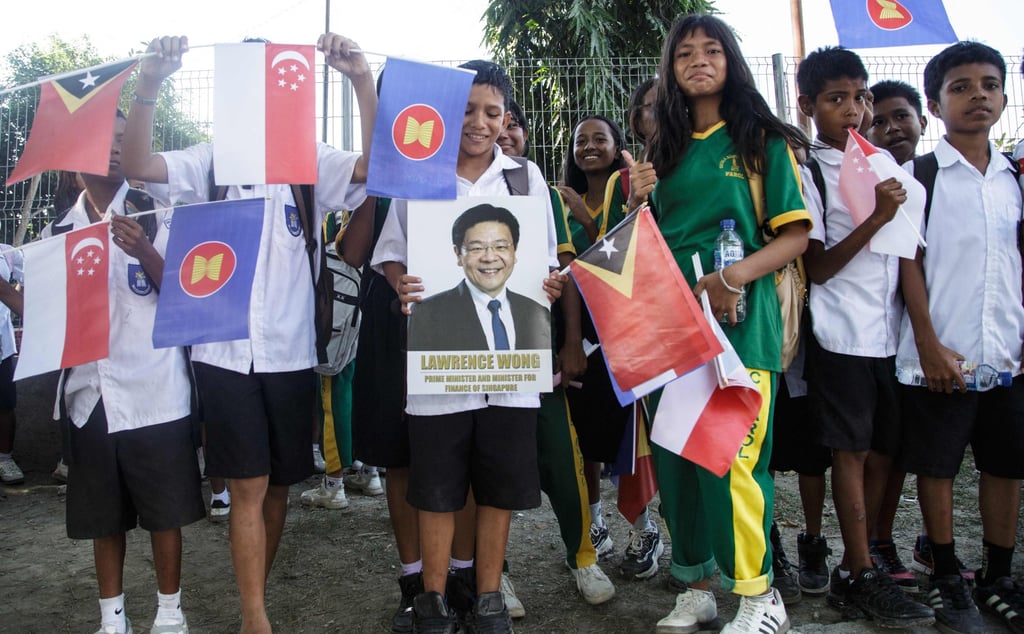 Students wait to welcome Singapore’s Prime Minister Laurence Wong along a road in Dili on Thursday. Photo: AFP