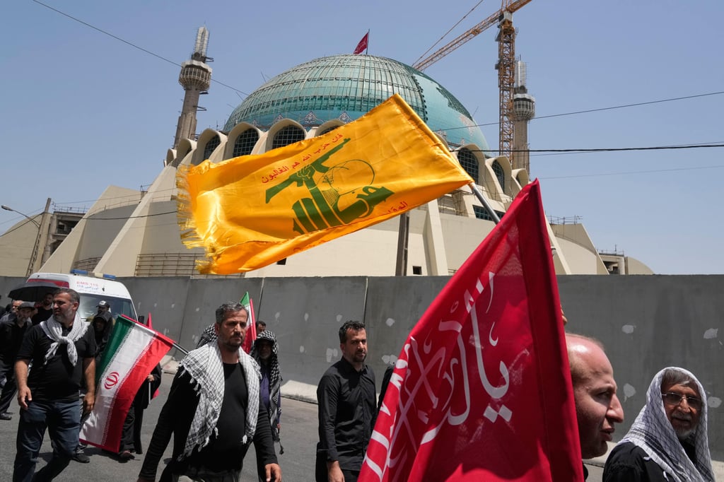 Mourners walk outside the Imam Khomeini Mosalla Grand Mosque as one carries a Hezbollah flag during the days-long funeral ceremonies for the late Iranian Supreme Leader Ayatollah Ali Khamenei and members of his family in Tehran, Iran, on Saturday. Photo: AP