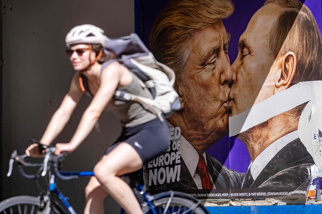 A woman cycles past a poster in Berlin in June depicting US President Donald Trump and Russian President Vladimir Putin kissing. Photo: AFP